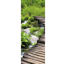Holzsteg über einen Bach in einer grünen Landschaft