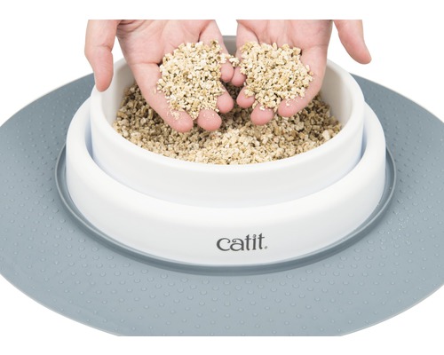 Katzenstreu in einer weißen Schale mit Unterlage und Händen, die Streu halten