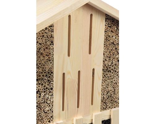 Detailansicht eines Insektenhotels aus Holz mit Bambusröhren und Schlitzen