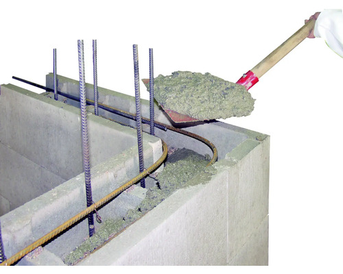 Du béton est versé à la pelle dans un bloc de coffrage.