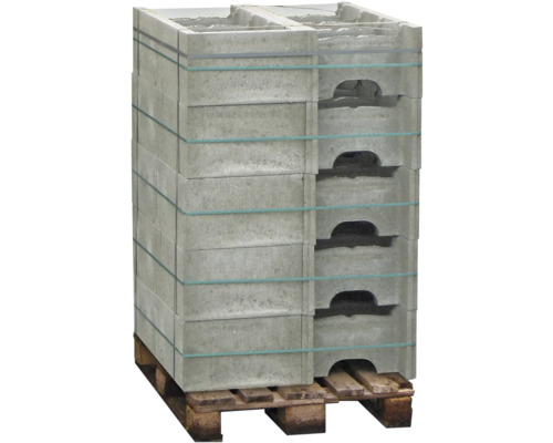 Une pile de blocs de béton gris avec des poignées, fixée par des bandes sur une palette en bois.