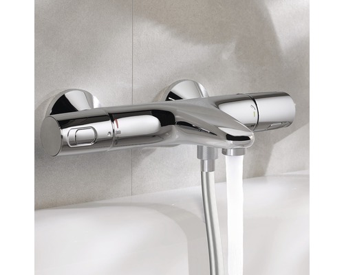 Mitigeur thermostatique apparent dans une salle de bain avec écoulement d''eau.