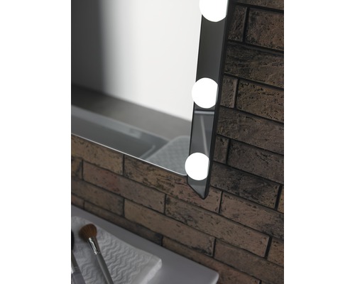 Vue détaillée d''un miroir éclairé à côté d''un mur de briques dans la salle de bain