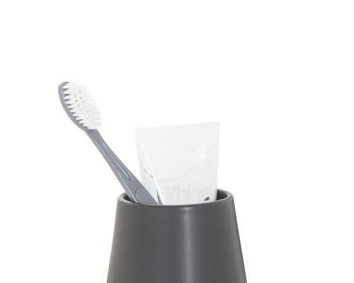 Zahnbürste und Zahnpasta in einem grauen Zahnputzbecher