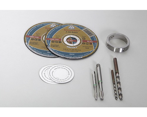 Zwei Trennscheiben, ein Metallring, Gewindebohrer und Spiralbohrer auf einem hellen Untergrund