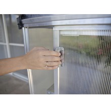 Eine Person öffnet die Tür eines Gewächshauses.