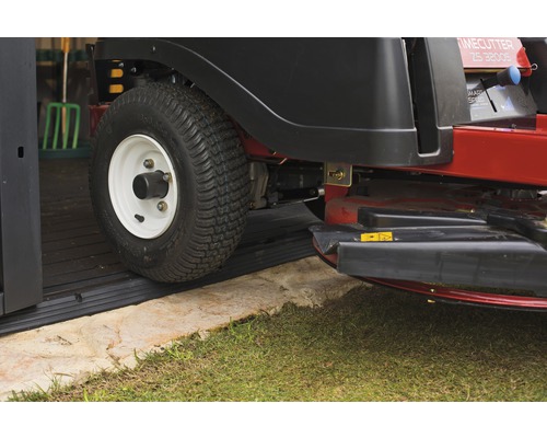 Tondeuse autoportée roulant sur un tapis en caoutchouc dans un garage