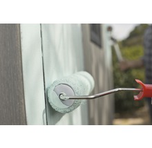 Gros plan d''une personne peignant un mur en bois avec un rouleau à peinture