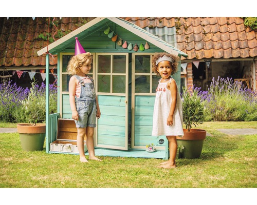 Maisonnette avec deux enfants dans le jardin. Décoration avec guirlande et chapeaux de fête.
