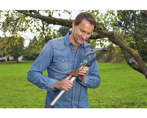 Un homme utilise une ébrancheur dans le jardin.