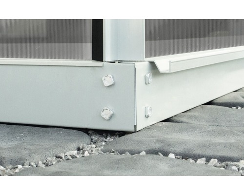 Detailansicht eines Gewächshausfundaments mit Schrauben auf Pflastersteinen