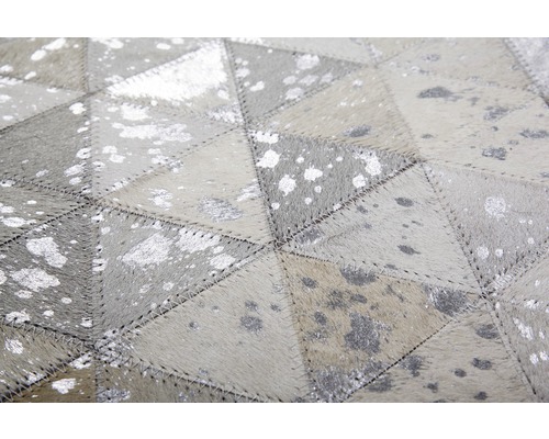 Gros plan d''un tapis fait de pièces de cuir avec un motif géométrique et des accents argentés.