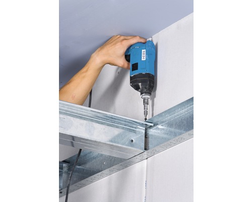 Un artisan fixe une plaque de plâtre sur une structure métallique à l''aide d''une visseuse sans fil.