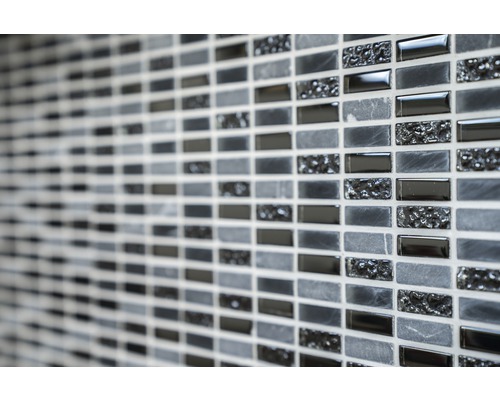 Gros plan d''un mur avec des carreaux de mosaïque dans différentes nuances de gris et textures.