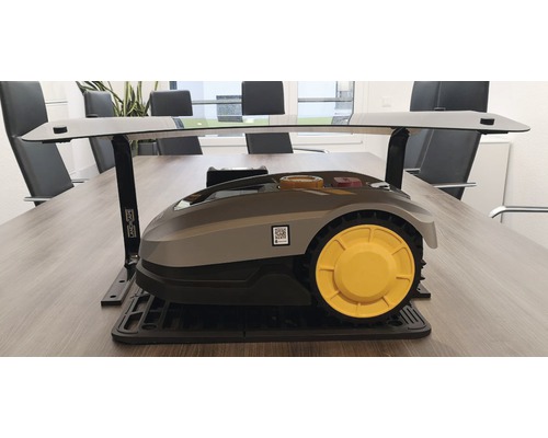 Mähroboter mit Ladestation auf einem Tisch