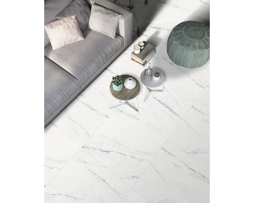 Heller Wohnraum mit Bodenfliesen in Marmoroptik, Sofa und Beistelltischen.