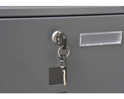 Detailansicht eines Briefkastens mit Schlüssel im Schloss und Namensschild