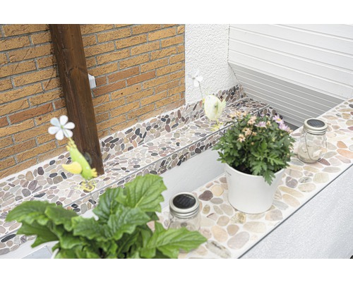 Dekorative Steinfliesen verschönern einen Außenbereich mit Pflanzen und Dekorationen.