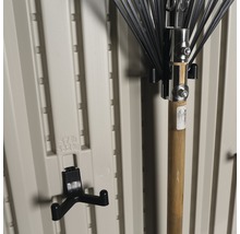 Support d''outils de jardin sur un mur en plastique beige avec un râteau à feuilles
