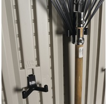 Outils de jardin et support d''outils sur un mur de cabanon de jardin beige.