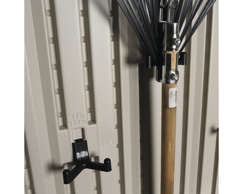Outils de jardin et support d''outils sur un mur de cabanon de jardin beige.