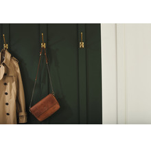 Szene mit einem Trenchcoat und einer Handtasche, die an goldenen Wandhaken hängen