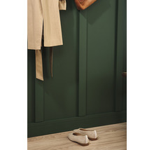 Garderobe mit beige Mantel, Tasche und Schuhen vor einer grünen Wand mit Holzpaneelen