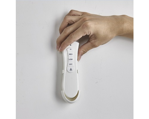 Main manipulant une télécommande pour contrôler un ventilateur