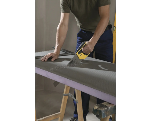 Une personne coupe une plaque de construction avec une scie à main sur une table de travail.