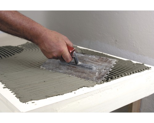 Application de colle à carrelage avec une spatule crantée