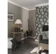 Séjour avec parquet, papier peint à décor floral et meubles en bois.