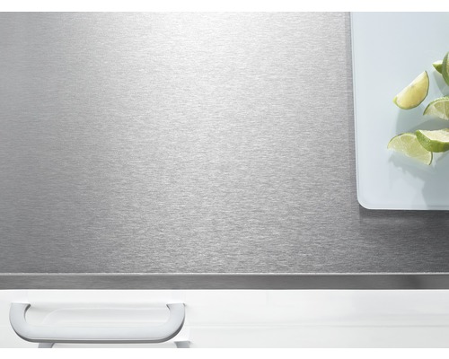 Plan de travail en acier inoxydable avec planche à découper et quartiers de citron vert