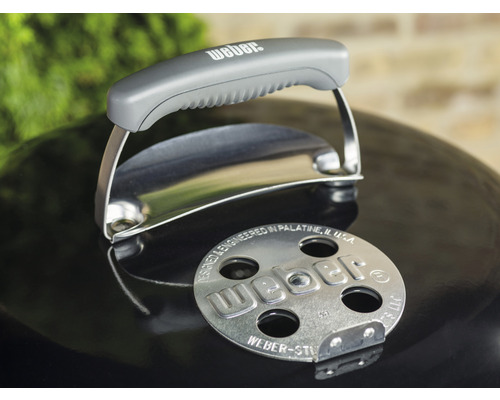 Vue détaillée d''un couvercle de barbecue Weber avec poignée et logo.