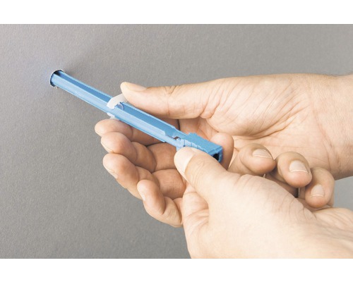 Une personne insère une cheville pour corps creux dans un mur