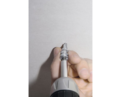 Un homme visse une cheville dans le mur à l''aide d''une visseuse sans fil.