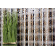 Plante artificielle verte décorative devant un mur de mosaïque en verre