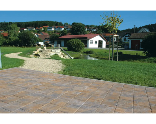 Verlegte Pflastersteine im Aussenbereich mit einem kleinen Bach und Häusern im Hintergrund