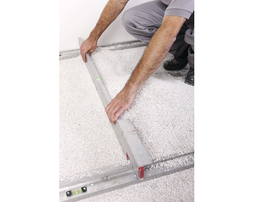 Artisan nivellant le composé d''égalisation de sol avec une règle