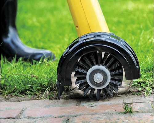 Detailansicht einer Fugenbürste beim Reinigen von Pflastersteinen