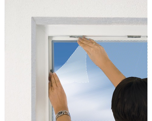 Person befestigt ein Insektenschutzgitter an einem Fenster