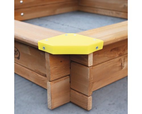 Detailansicht eines Sandkastens aus Holz mit gelber Eckabdeckung