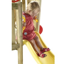 Fille glissant sur un toboggan de jeu en bois