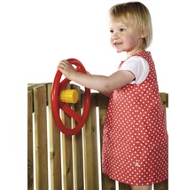 Un enfant joue avec un volant rouge sur une aire de jeux en bois.
