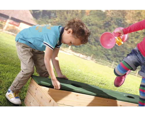 Kinder spielen mit einem Sandkasten im Garten.