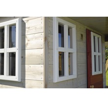 Détail d''une cabane de jeu avec revêtement en bois et encadrements de fenêtres blancs.
