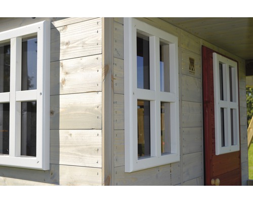 Détail d''une cabane de jeu avec revêtement en bois et encadrements de fenêtres blancs.