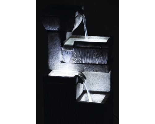 Dekorativer Zimmerbrunnen aus Stein mit Wasserkaskaden und Beleuchtung.