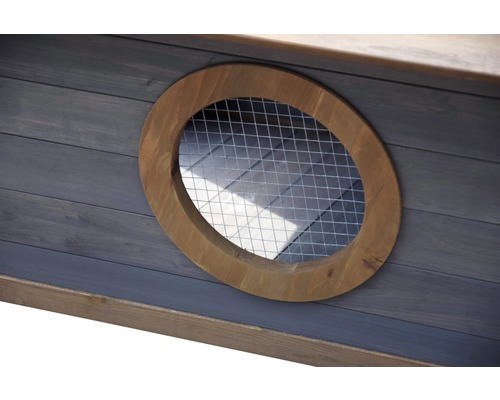 Vue détaillée d''une fenêtre ronde avec grille dans une maison en bois