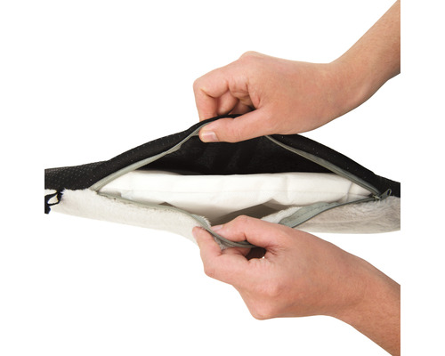 Hände öffnen den Reißverschluss eines Hundebetts.