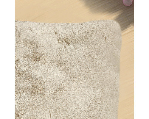 Detailansicht eines beigen, rechteckigen Hochflorteppichs.